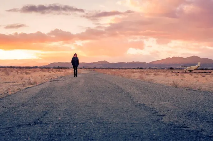 USA, California, Joshua Tree, young guy walks along a road while sunset