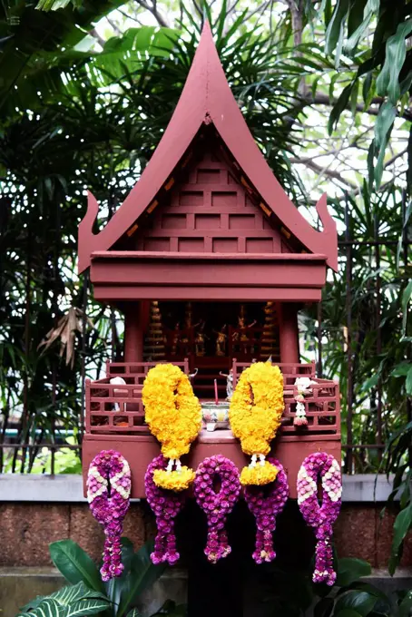 Thailand, Bangkok, Thai-style house replica as small buddhist chapel decorated with flowers