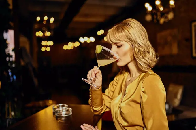 Elegant woman drinking cocktail in a bar