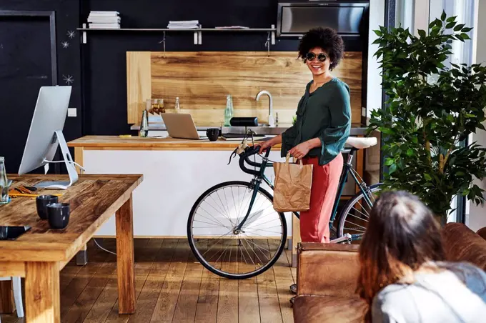 Young woman with bicycle arriving in modern office