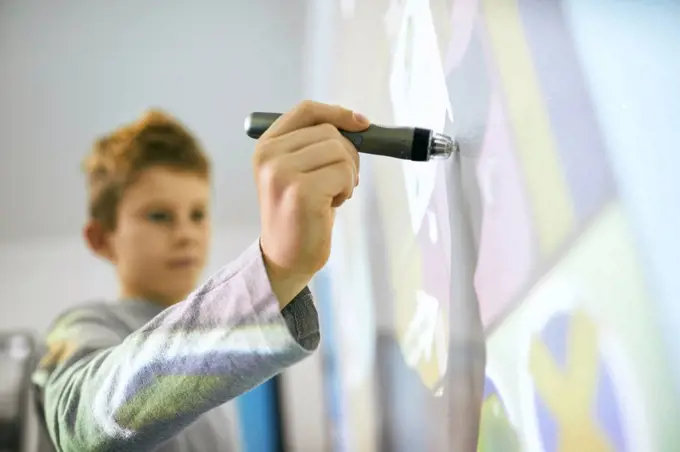 Student in class using digitized pen at interactive whiteboard