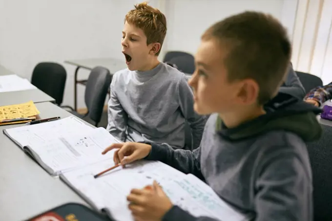 Students learning in class with boy yawning