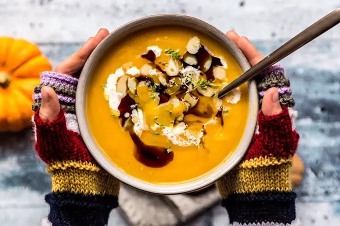 Girl's hands holding bowl of creamed pumpkin soup