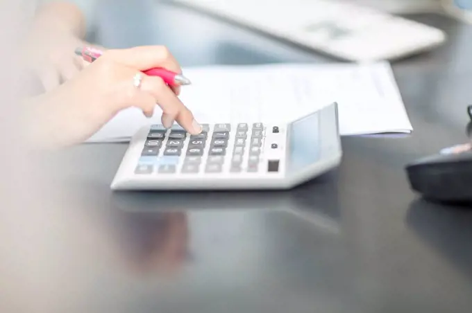 Woman at desk in office using calculator