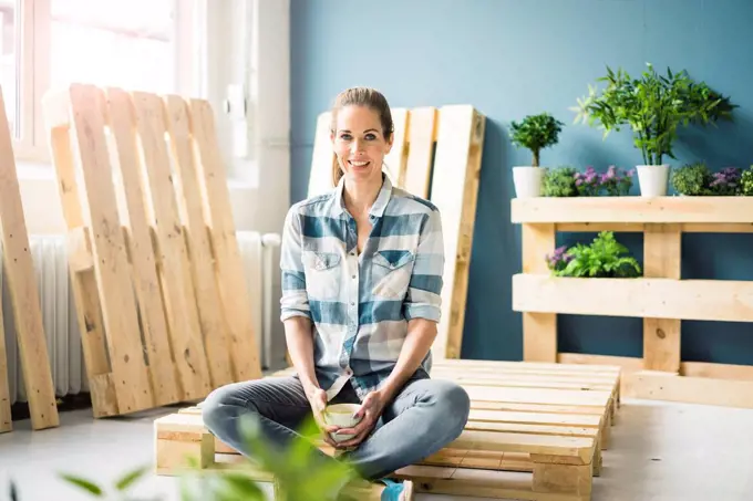 Beautiful woman taking a break from refurbishing her home with pallets, drinking coffee