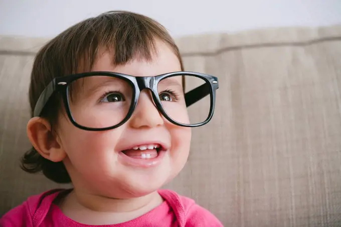 Portrait of laughing baby girl wearing oversized glasses