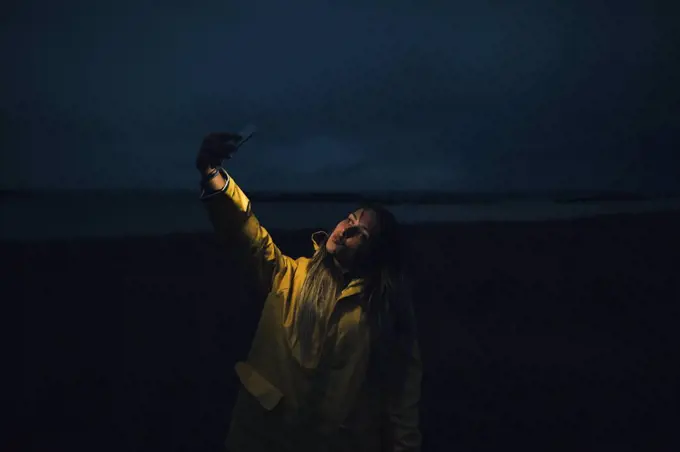 France, Brittany, Landeda, Dunes de Sainte-Marguerite, woman taking a selfie on the beach at night