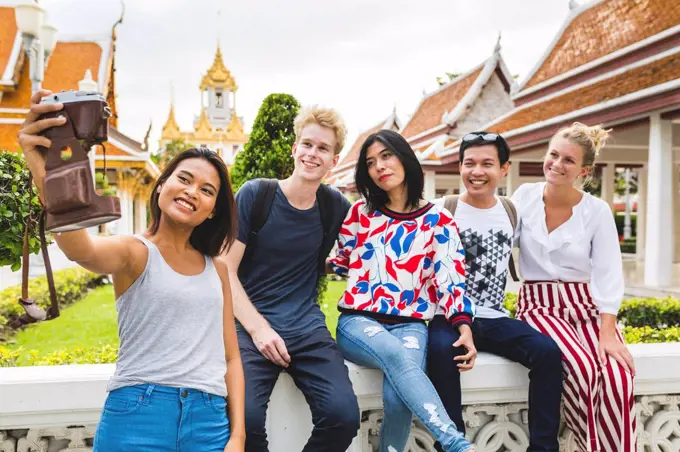 Thailand, Bangkok, five friends taking selfie with smartphone in front of temple complex