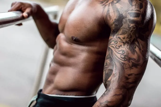 Tattooed biceps of physical athlete, close-up