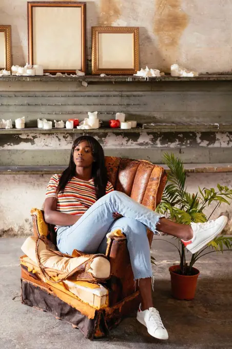 Portrait of cool young woman sitting on an old leather chair in a loft