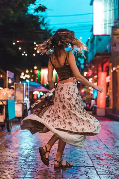 Thailand, Bangkok, young woman in the city dancing on the street at night