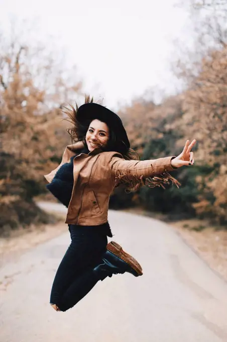 Portrait of happy young woman jumping in the air outdoors