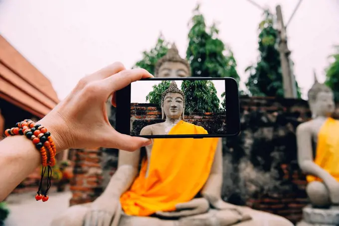 Thailand, Ayutthaya, Wat Yai Chai Mongkhon, taking a photo from Buddha with smartphone