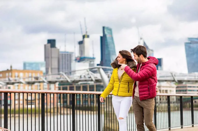 UK, London, young couple walking on bridge watching something