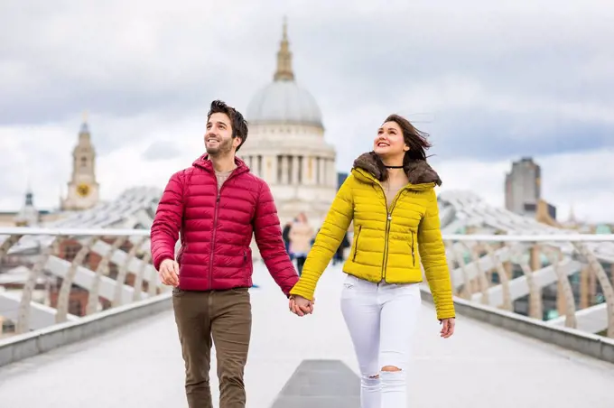UK, London, young couple walking hand in hand on bridge in front of St Pauls Cathedral