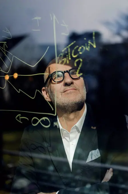 senior businessman brainstorming, drawing formulas on window pane
