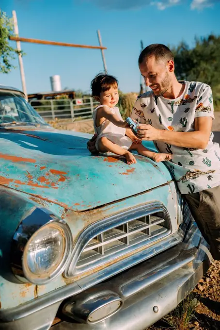 USA, Arizona, Father and baby playing with a reproduction of an old vintage car, at Route 66