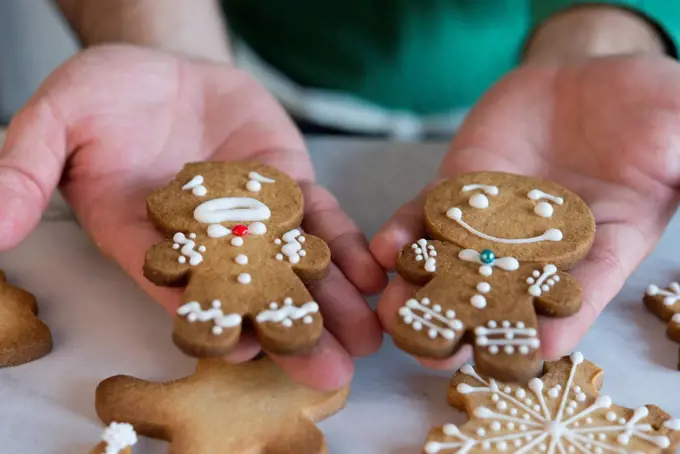 Man's hands holding two different Gingerbread Men, close-up