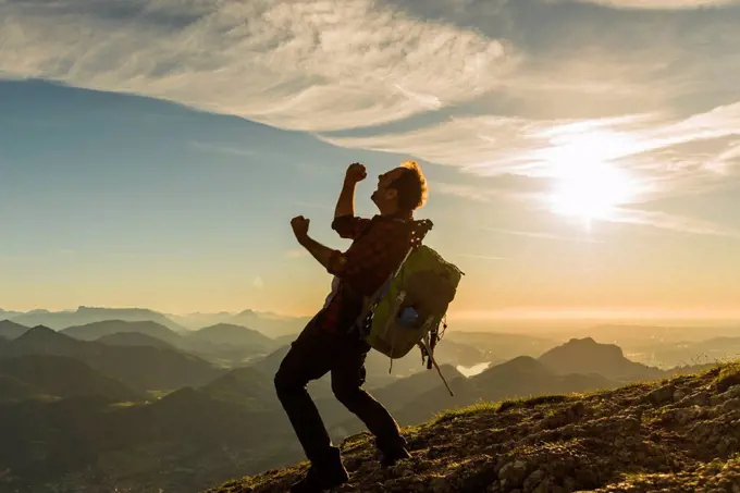 Austria, Salzkammergut, Hiker reaching summit, raising arms, cheering