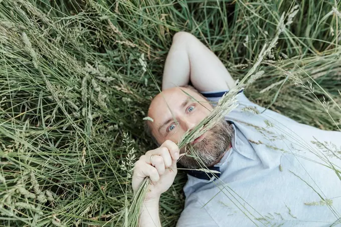 Portrait of mature man lying on grass pulling funny faces