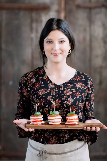 Portrait of smiling woman serving Caprese Salad