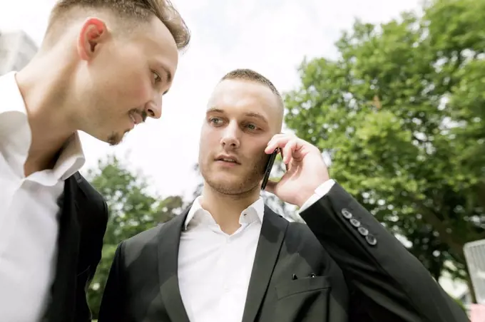 Two young businessmen with cell phone outdoors