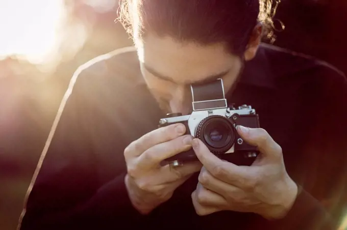 Young man photographing with analogue camera