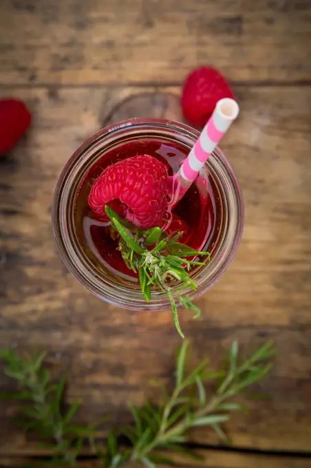 Glass bottle of homemade raspberry lemonade flavoured with rosemary