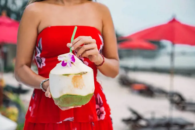 Thailand, woman holding fresh coconut, partial view