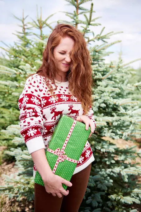 Redheaded young woman with Christmas present outdoors