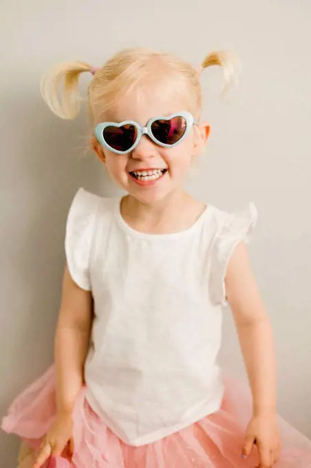 Portrait of blond little girl wearing heart-shaped sunglasses