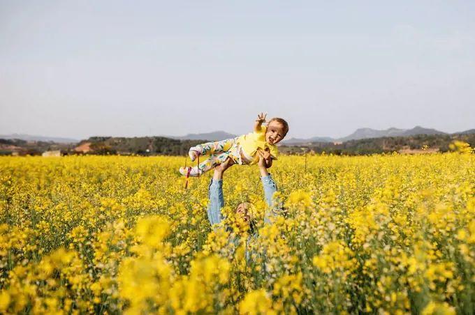Spain, father and baby girl having fun together in a rape field