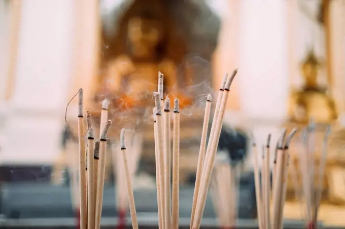Thailand, Bangkok, incense burning in front of Buddha statues in a Buddhist temple