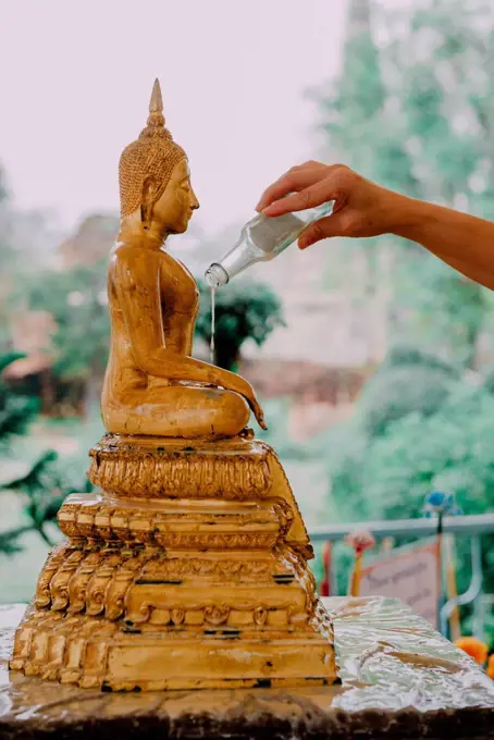 Thailand, Bangkok, Faithful people bathing a statue of the Buddha with a sacred herbal liquid