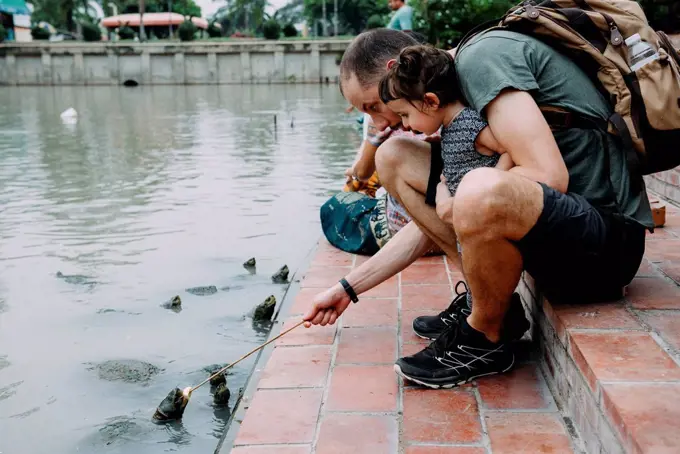 Thailand, Bangkok, Ayutthaya, father and daughter feeding turtles