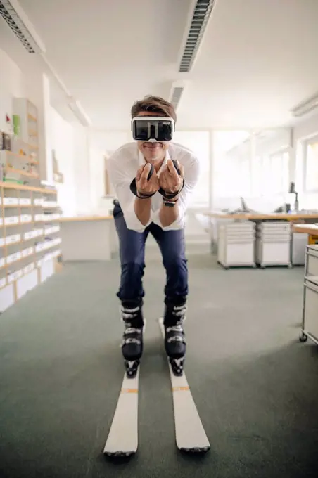 Businessman skiing in office, using VR glasses
