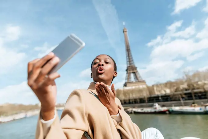 France, Paris, Woman taking a selfie with the Eiffel tower in the background