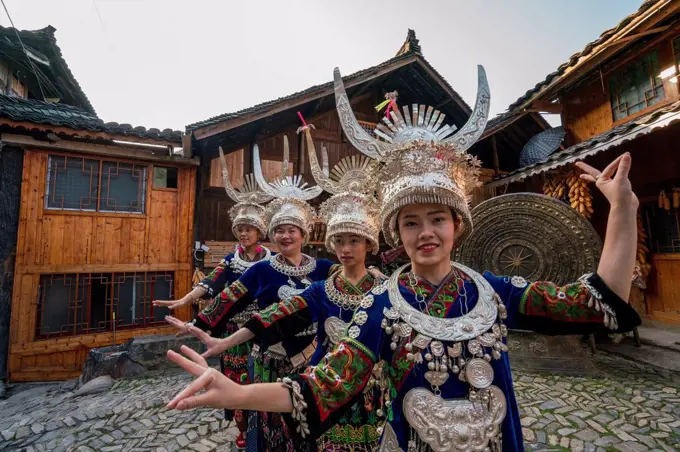 China, Guizhou, Miao women wearing traditional dresses and headdresses posing on village square