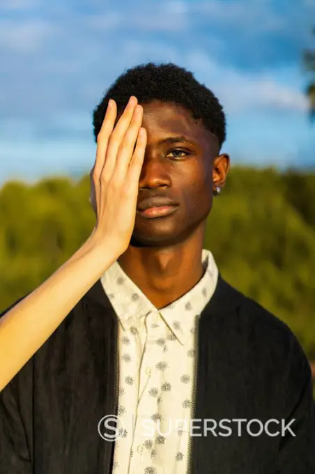 Hands covering eyes of a young black man