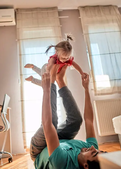 Father playing with his little daughter at home