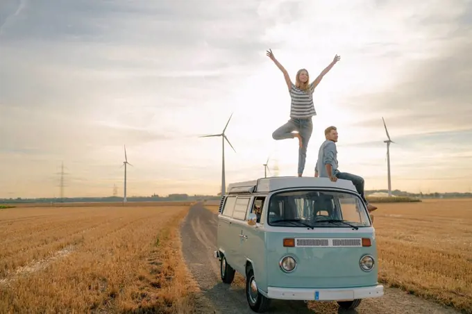 Young couple on roof of a camper van in rural landscape