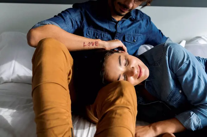 Tattooed man cuddling up with girlfriend