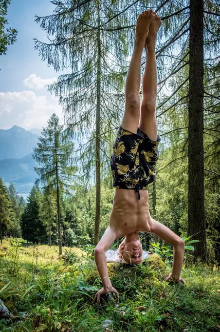 Teenage boy doing a headstand in forest