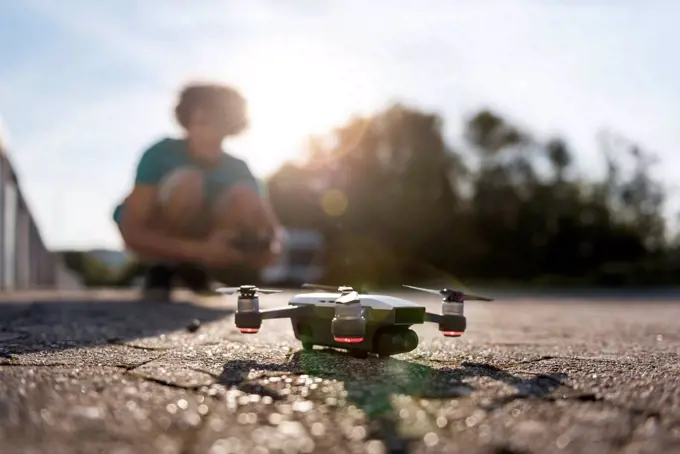 Boy landing his drone on the street