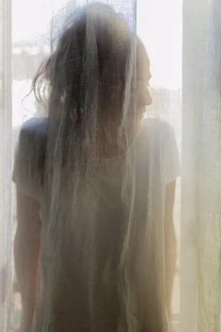 Silhouette of a young woman behind a curtain