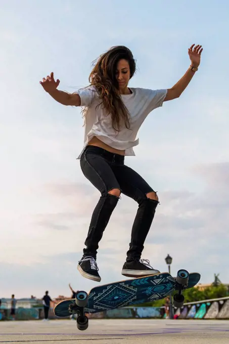 Young woman doing a skateboard trick in the city