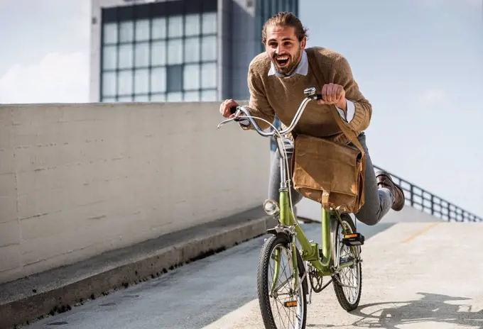 Laughing businessman riding down a ramp on his bicycle