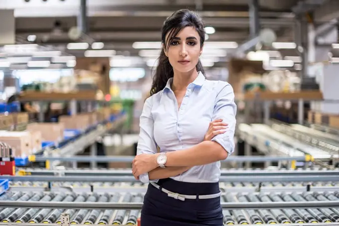 Portrait of confident woman at conveyor belt in factory