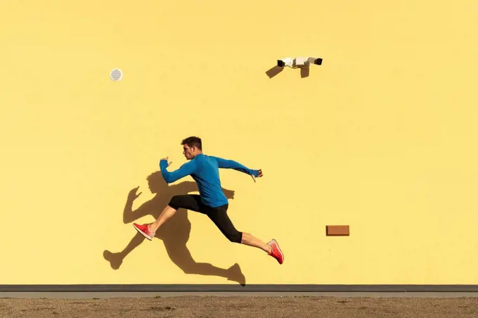Sportive man exercising at yellow wall with CCTV camera