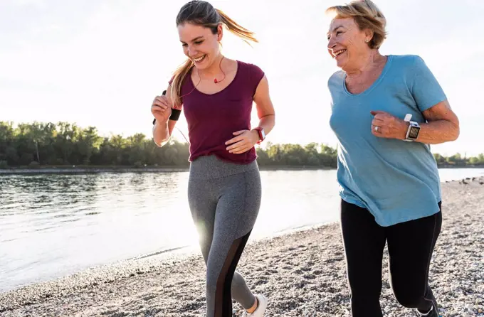 Granddaughter and grandmother having fun, jogging together at the river
